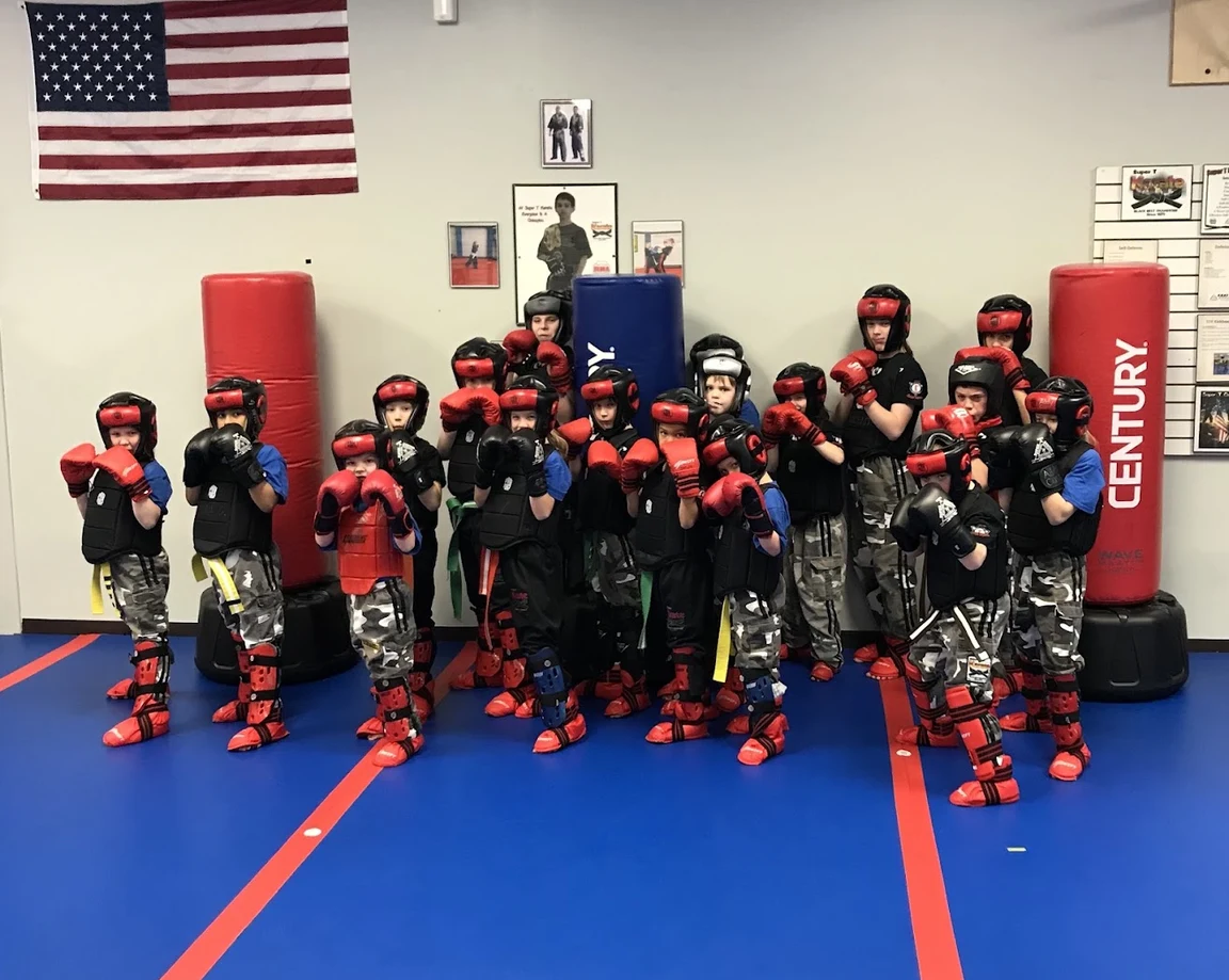 Kids in sparring gear lined up in front of the flag at Super T Karate in Grand Rapids