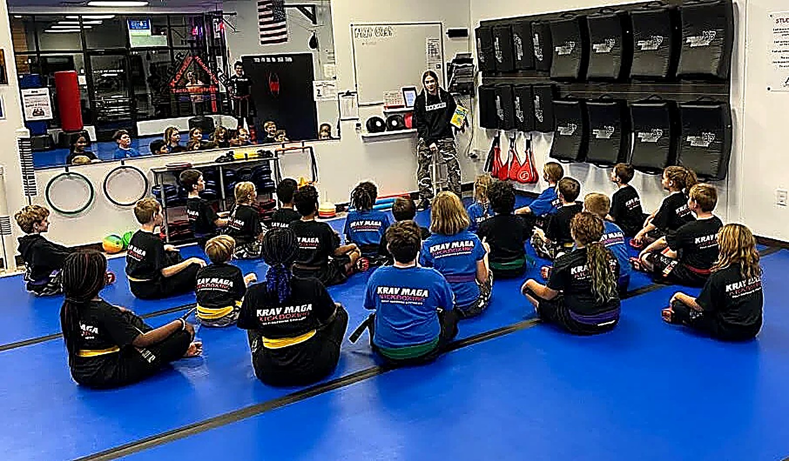 Students sitting on the mat listening to their instructor during a character lesson at Super T Karate
