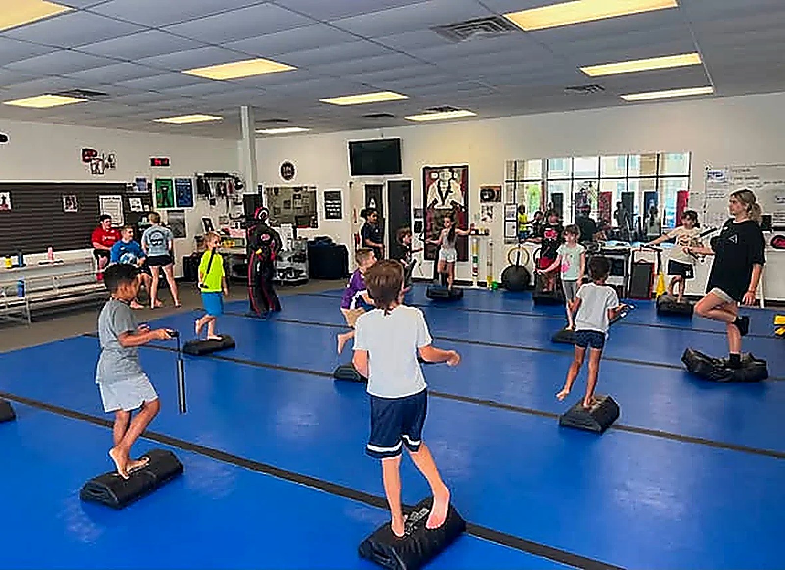Kids balancing on stepping pods during warm-up games at Super T Karate in Grand Rapids
